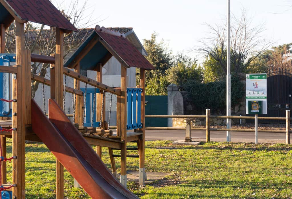 Parco giochi con scivolo in legno e strutture per bambini all'aperto.