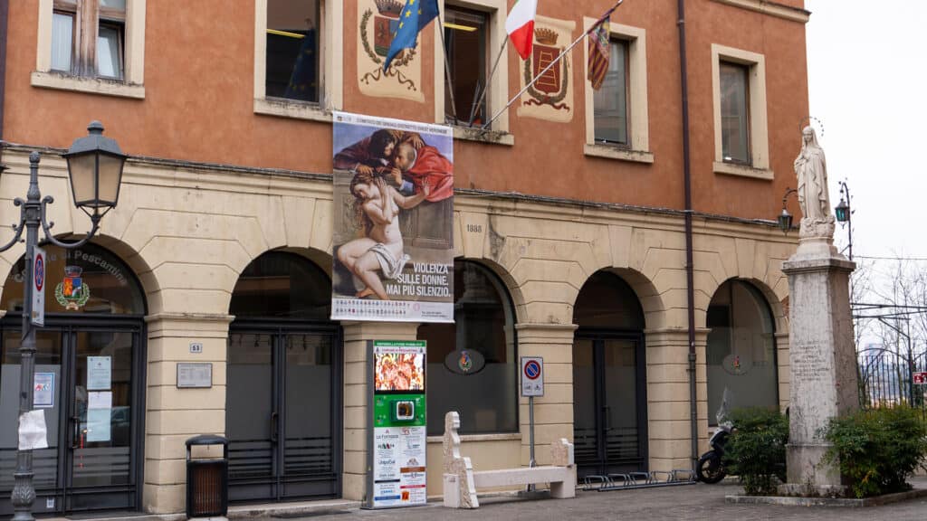 Scultura artistica in piazza con statue e bandiere italiane ed europee.