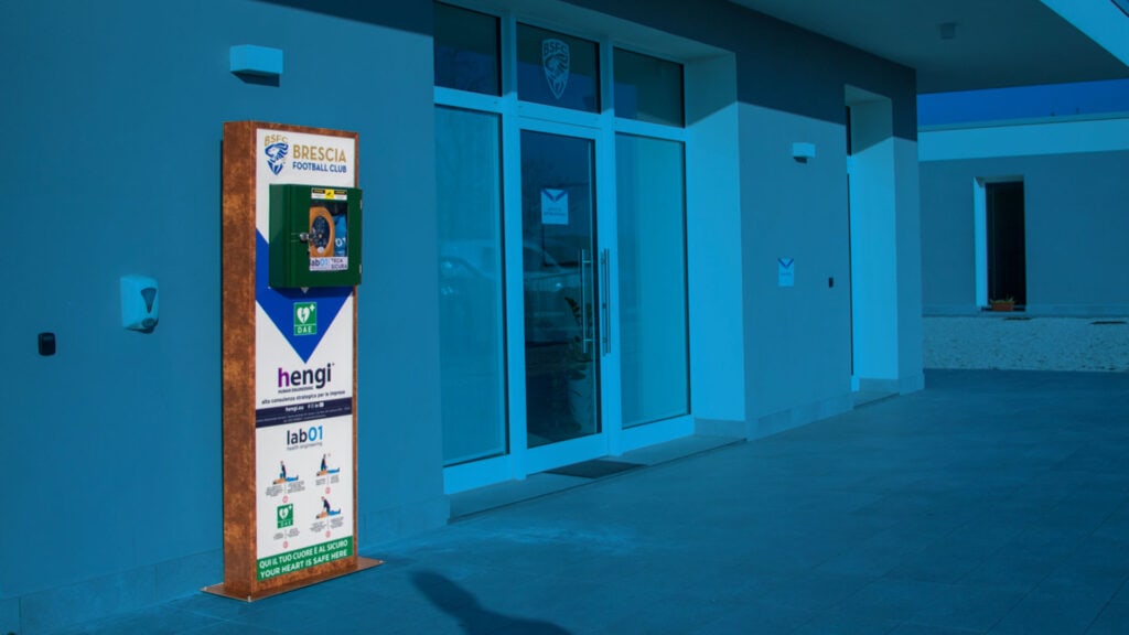 Pannello informativo con logo Brescia Calcio e pubblicità, situato all'esterno di un centro sportivo.
