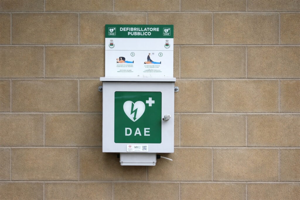 Defibrillatore pubblico Wall DAE per emergenze cardiache, installato su parete in ambiente esterno.
